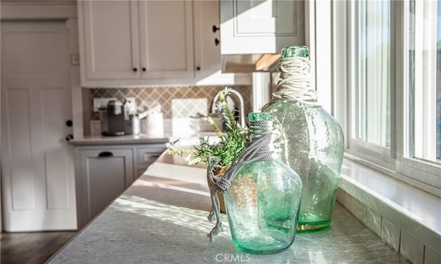 bar featuring backsplash and white cabinetry