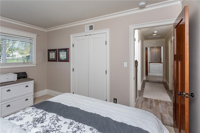 bedroom featuring a closet, ornamental molding, and light hardwood / wood-style flooring