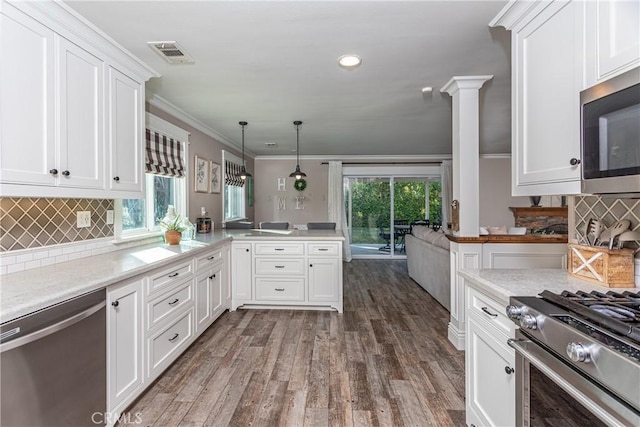 kitchen featuring decorative light fixtures, appliances with stainless steel finishes, white cabinetry, and decorative columns