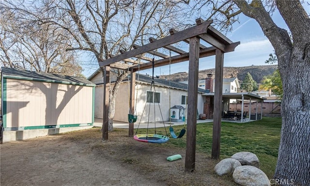 view of yard with a playground, a mountain view, and a shed