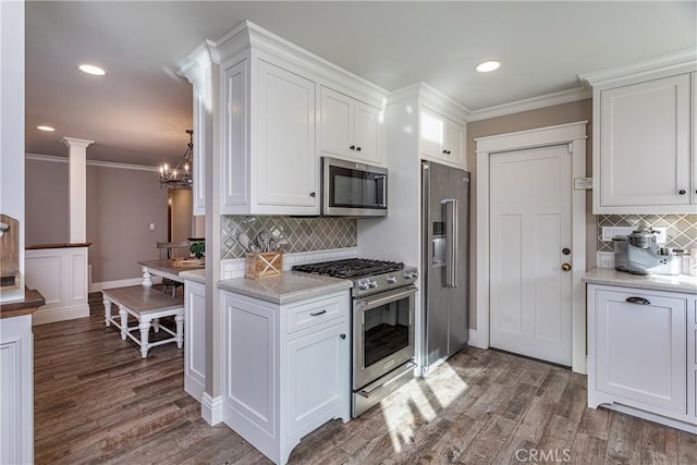 kitchen featuring decorative columns, premium appliances, and white cabinets