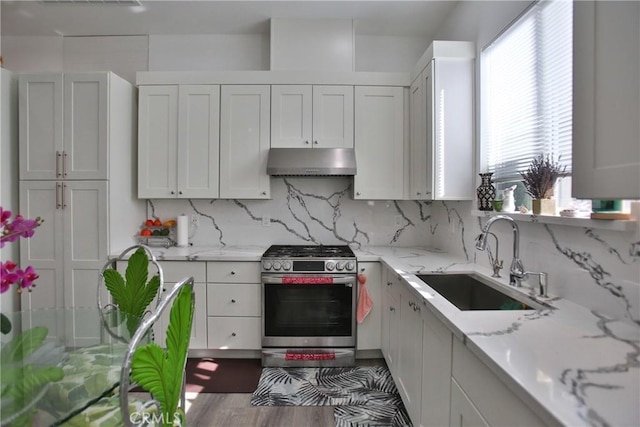 kitchen featuring stainless steel range with gas cooktop, tasteful backsplash, light stone countertops, white cabinets, and sink