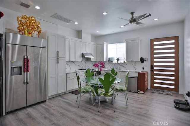 kitchen with backsplash, stainless steel built in refrigerator, and light wood-type flooring