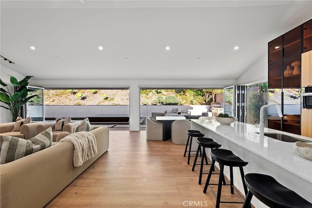 living area featuring lofted ceiling, recessed lighting, and light wood finished floors