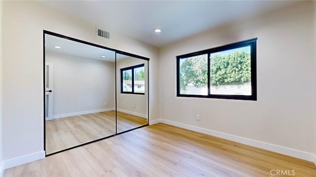 unfurnished bedroom with light hardwood / wood-style flooring and a closet