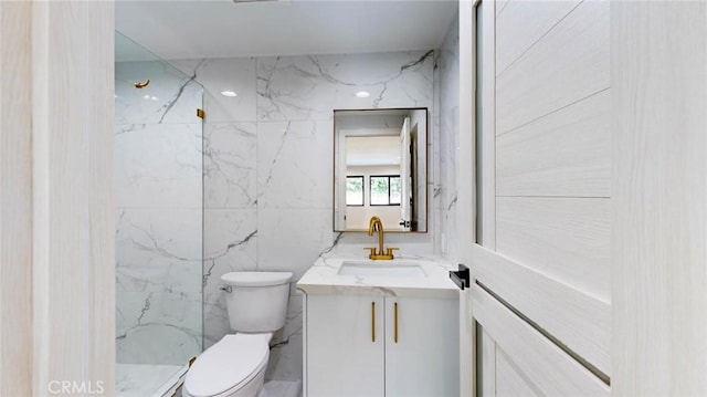 bathroom featuring vanity, a shower, tile walls, and toilet