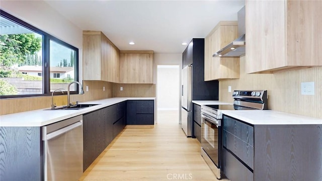 kitchen with appliances with stainless steel finishes, sink, backsplash, light brown cabinets, and light wood-type flooring