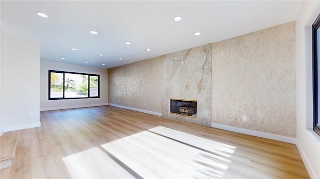 unfurnished living room featuring light wood-type flooring and a high end fireplace