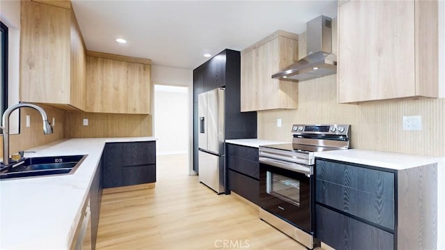 kitchen featuring light brown cabinetry, wall chimney range hood, stainless steel appliances, and sink