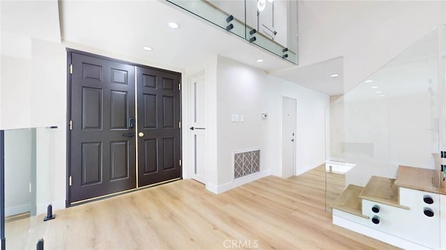 entryway with a towering ceiling and light wood-type flooring