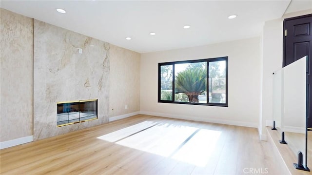 unfurnished living room featuring a high end fireplace and light hardwood / wood-style flooring