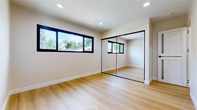 unfurnished bedroom with light hardwood / wood-style flooring and a closet