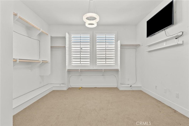 walk in closet featuring light colored carpet and a chandelier