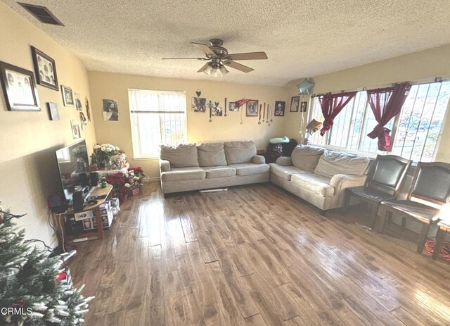 living room with hardwood / wood-style flooring, a textured ceiling, and ceiling fan