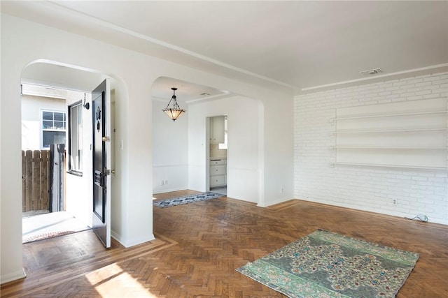 empty room with brick wall and dark parquet floors