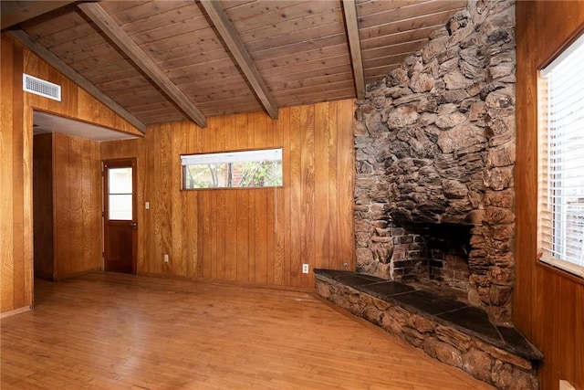 unfurnished living room with wood ceiling, lofted ceiling with beams, light hardwood / wood-style flooring, wooden walls, and a fireplace