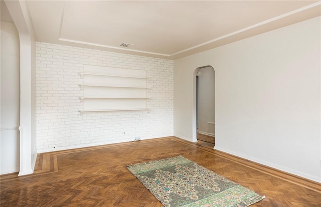 empty room with brick wall and dark parquet flooring