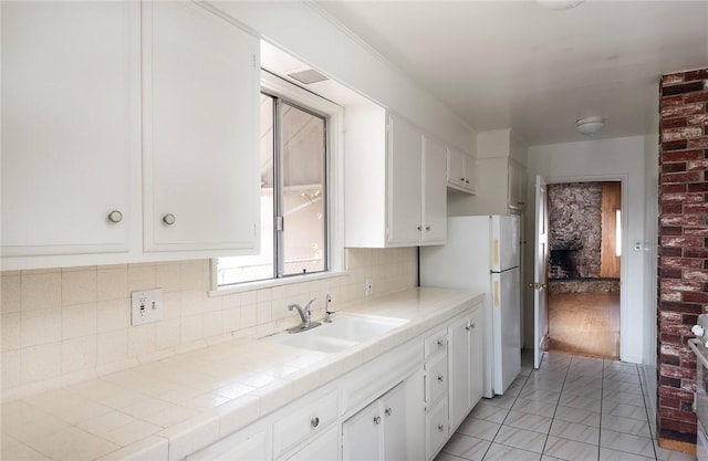 kitchen featuring tile counters, sink, decorative backsplash, and white cabinets