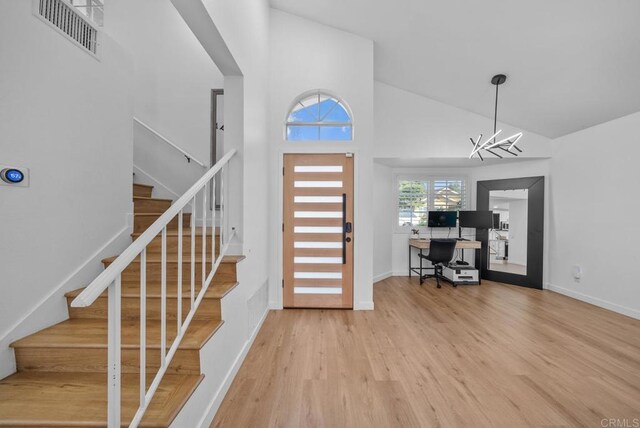 foyer with high vaulted ceiling, wood-type flooring, and a notable chandelier