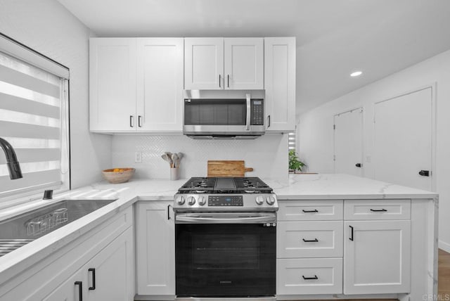 kitchen featuring light stone counters, sink, white cabinets, and stainless steel appliances