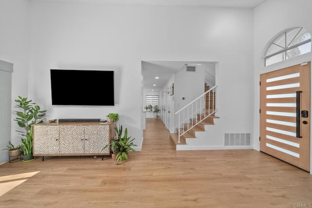 entryway with light hardwood / wood-style floors and a towering ceiling