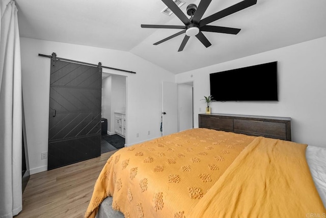 bedroom with ensuite bath, wood-type flooring, vaulted ceiling, ceiling fan, and a barn door