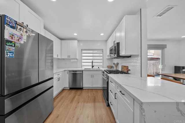 kitchen featuring white cabinets, plenty of natural light, light stone counters, and stainless steel appliances