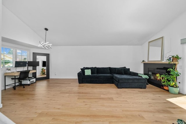 living room featuring light wood-type flooring, a chandelier, and vaulted ceiling