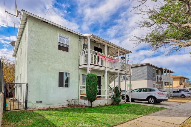 view of front of house featuring a balcony and a front yard