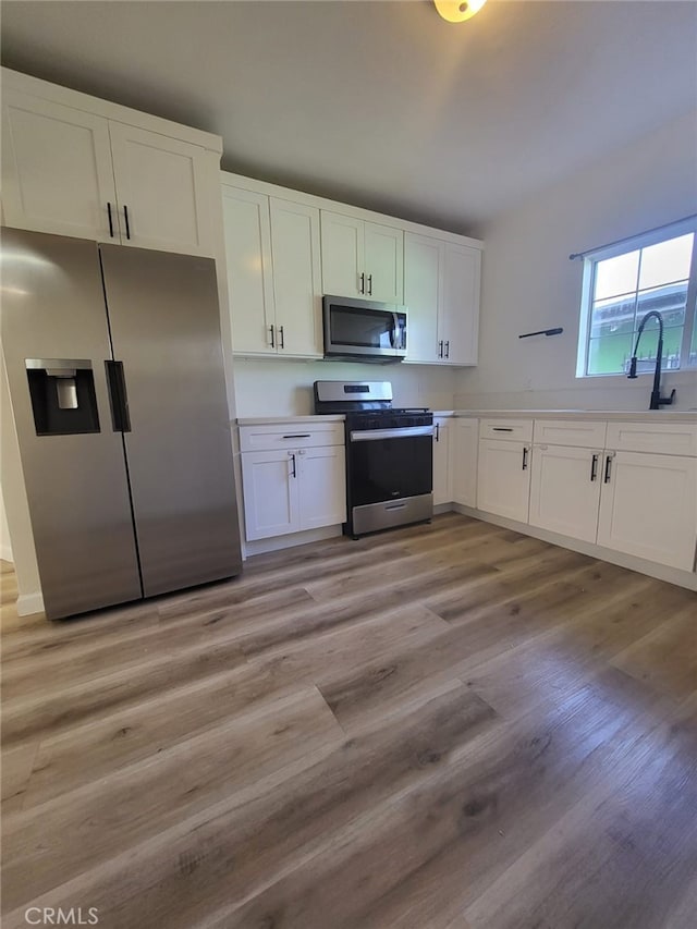 kitchen with light hardwood / wood-style floors, white cabinets, appliances with stainless steel finishes, and sink