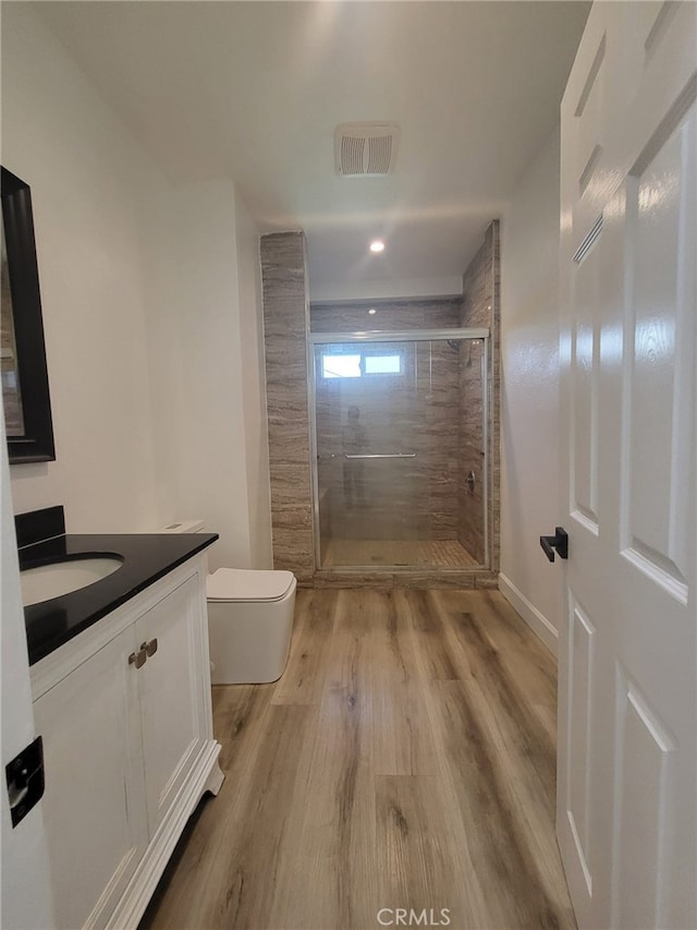 bathroom with a shower with shower door, wood-type flooring, toilet, and vanity