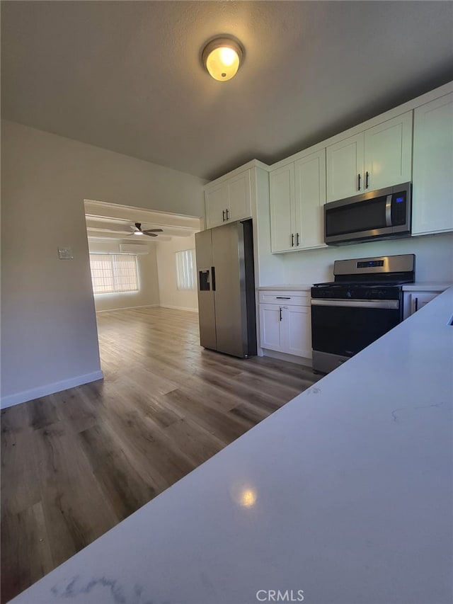 kitchen with ceiling fan, white cabinets, stainless steel appliances, and hardwood / wood-style floors