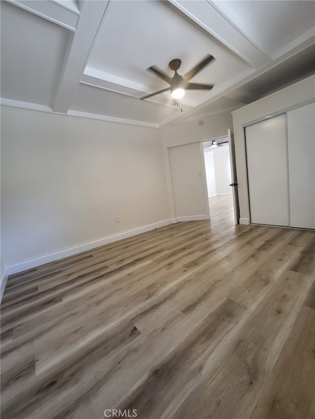 unfurnished bedroom with hardwood / wood-style flooring, a closet, beam ceiling, and ceiling fan