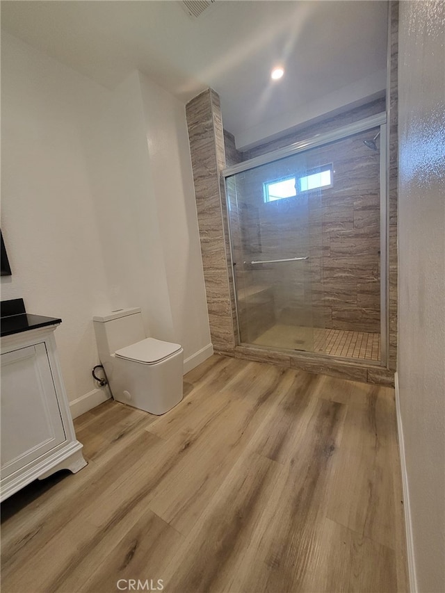 bathroom featuring wood-type flooring, toilet, and walk in shower