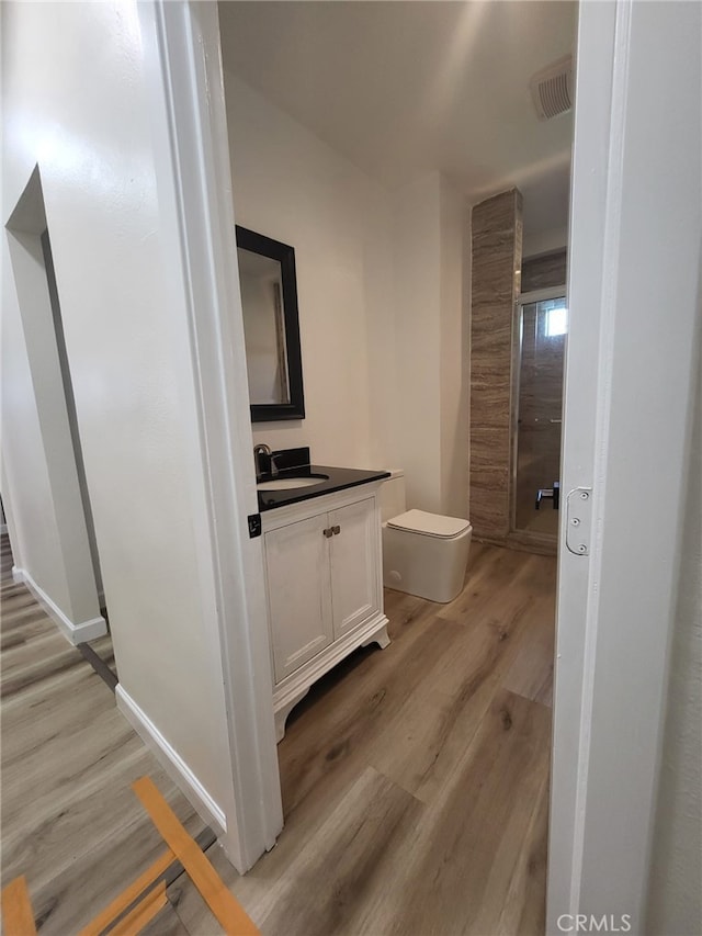 bathroom featuring toilet, vanity, and hardwood / wood-style floors