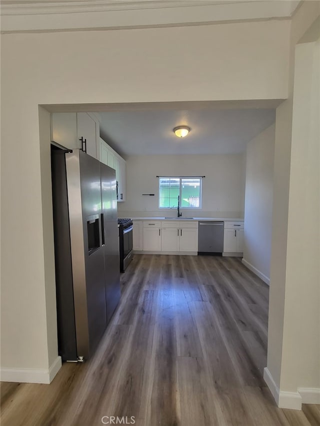 kitchen featuring appliances with stainless steel finishes, sink, dark hardwood / wood-style flooring, and white cabinetry