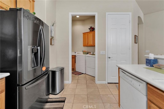 kitchen featuring stainless steel refrigerator with ice dispenser, light tile patterned floors, washer and dryer, and white dishwasher