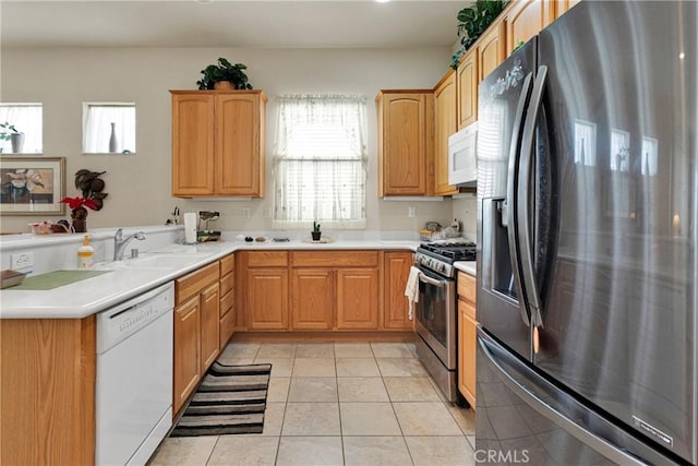 kitchen with sink, kitchen peninsula, stainless steel appliances, and light tile patterned flooring