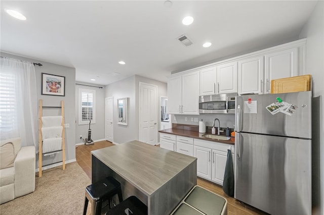 kitchen with hardwood / wood-style flooring, sink, white cabinetry, and appliances with stainless steel finishes