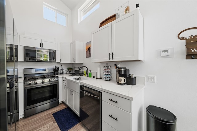 kitchen with light stone countertops, white cabinets, appliances with stainless steel finishes, and sink