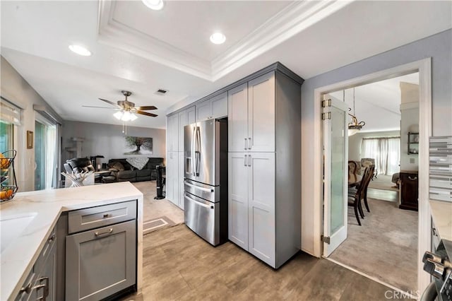 kitchen featuring stainless steel fridge with ice dispenser, decorative light fixtures, a raised ceiling, ceiling fan, and gray cabinets