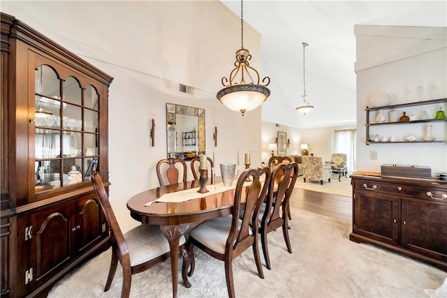 carpeted dining space featuring lofted ceiling