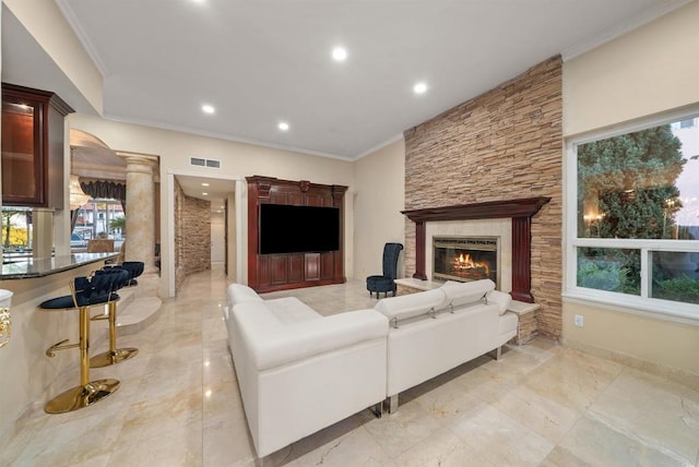 living room with ornate columns, a healthy amount of sunlight, and a stone fireplace