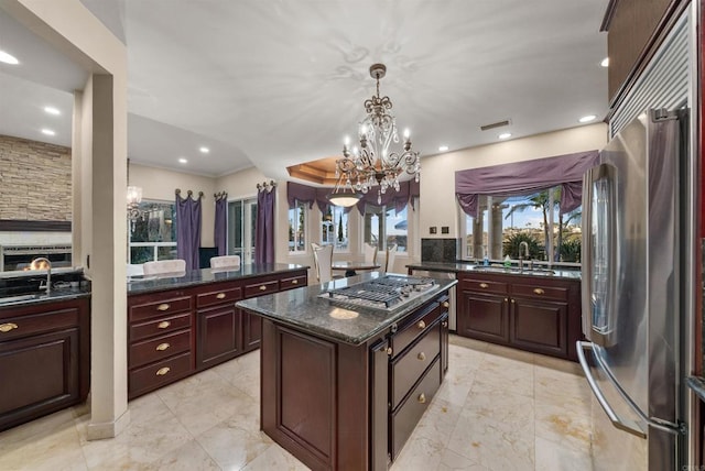 kitchen with appliances with stainless steel finishes, a center island, decorative light fixtures, an inviting chandelier, and sink