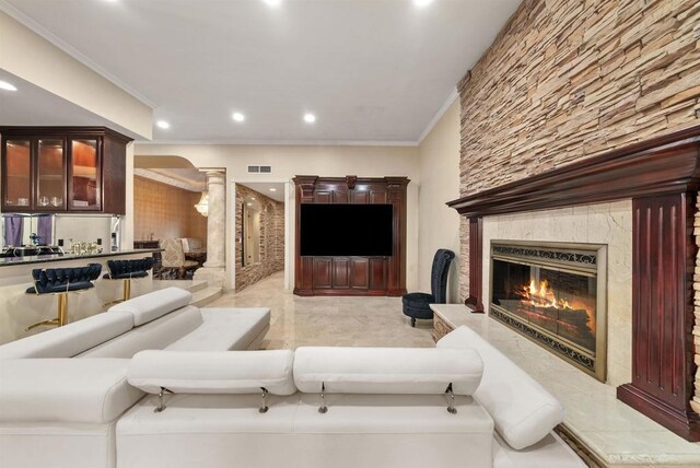 living room with a high end fireplace, ornamental molding, indoor bar, and decorative columns