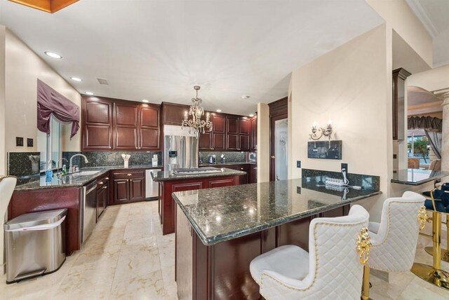 kitchen with stainless steel appliances, dark stone countertops, sink, hanging light fixtures, and kitchen peninsula