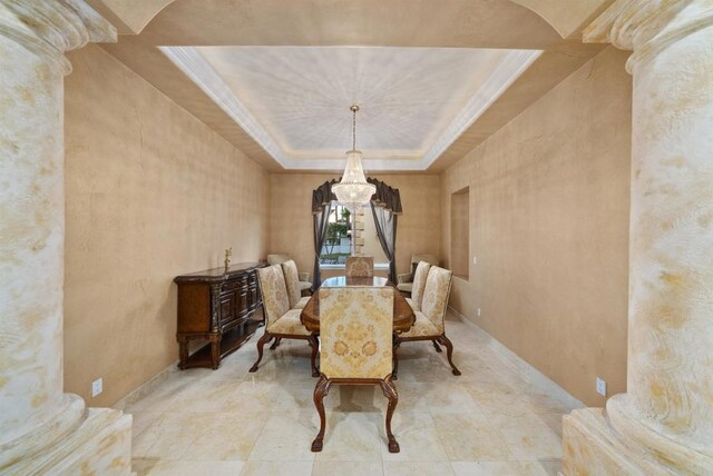 dining room featuring a raised ceiling and ornate columns