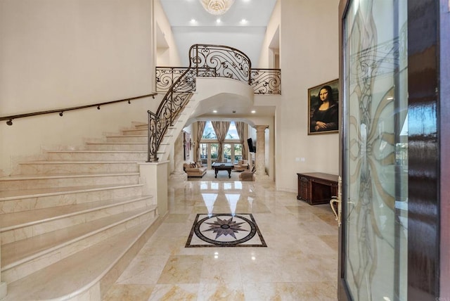 foyer entrance featuring a towering ceiling and decorative columns