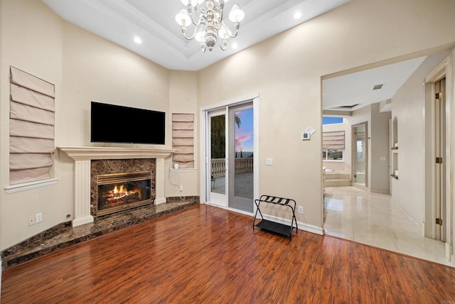 unfurnished living room with an inviting chandelier, a high end fireplace, and hardwood / wood-style flooring