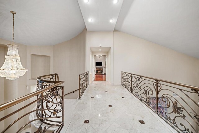 hallway with vaulted ceiling and a notable chandelier